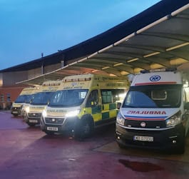 Nowy ambulans do transportu osób niepełnosprawnych na parkingu przed bazą medyczną.